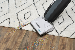 A vacuum cleaner is being used on a rug.