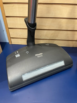 A reconditioned Miele Brilliant vacuum cleaner head on a blue counter with a wooden background from Sew & Vac.