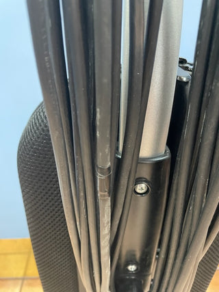 Close-up of the back of an office chair showing the metal frame, black mesh backrest, and multiple black cables and wires bundled together, reminiscent of the organized design found in a Sew & Vac Riccar R10S vacuum with a metal brush roll.