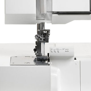 Close-up of the Husqvarna Viking Huskylock S21 overlock machine by Husqvarna Viking, focusing on the needle area and dual measurement markings in inches and millimeters.