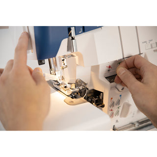 Close-up of hands adjusting settings and threading on the Husqvarna Viking Amber Air S400 Overlock Machine, which features convenient one-touch air threading.