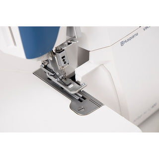 Close-up of the Husqvarna Viking Amber Air S400 Overlock Machine’s needle and presser foot, showing its white and blue design—ideal for precise overlock sewing with easy one-touch air threading.