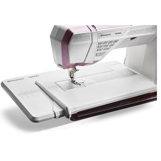 The Imagine Sewing & Vacuum Husqvarna Viking Epic Quilt 97 with Quilting Kit is a computerized sewing machine featuring an extended work surface, display screen, and multiple control buttons.