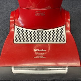 A red 2-Miele Salsa Upright CR vacuum cleaner with automatic height adjustment and HEPA filtration, seen from above on a dark carpeted floor.