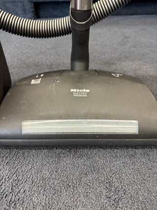 Close-up of a Used Miele Complete C3 Canister Vacuum from Sew & Vac with premium power head on dark carpet, delivering advanced cleaning and HEPA filtration.