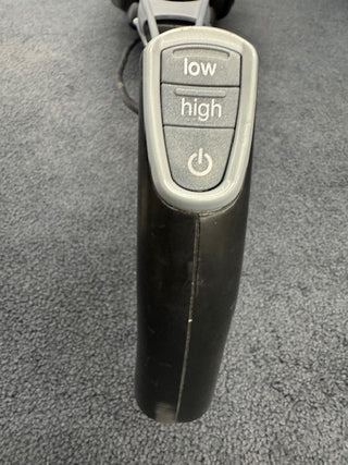 Close-up of the Oreck Magnesium RS Swivel-Steering Upright Vacuum RLW1500RS control panel, highlighting "low," "high," and power buttons on a gray carpet—showcasing this lightweight, certified reconditioned Oreck upright vacuum.
