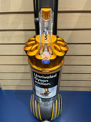 Sew & Vac Dyson UP19 Multifloor 2 on display, featuring a transparent dust bin and yellow accents, with a label highlighting its "Unrivaled Dyson suction." This certified refurbished model looks almost like new and comes with brand new filters.