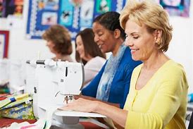 A group of women sewing on Sew & Vac machines in a classroom, while chatting and sharing their sewing techniques.