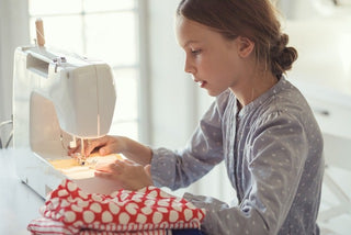 A young girl operating a Sew & Vac sewing machine, stitching intricate patterns.