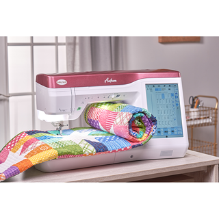 The 37-Baby Lock Anthem Quilting & Sewing Machine stitches a colorful quilt on a table in a sunlit room, highlighting its built-in stitch features.