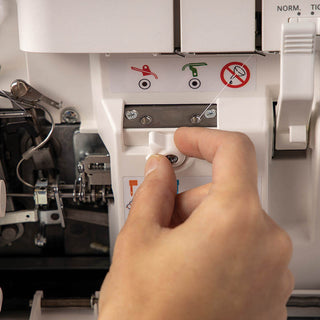 A person is holding a button on a PFAFF Admire Air 5000 sewing machine.