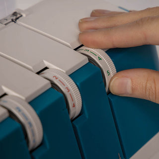 A person is using a Pfaff Admire Air 5000 sewing machine with blue and white buttons.