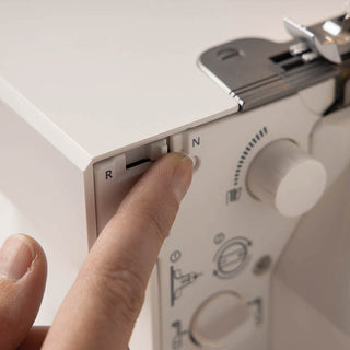 A person is holding a button on a PFAFF sewing machine.