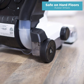 Close-up of the simplicity Simplicity S20EZM Allergy Bagged Upright’s rubber wheels on hardwood flooring, with a corner label stating “Safe on Hard Floors, Rubber Wheels.”.