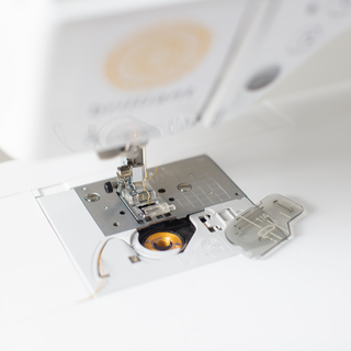 A white Baby Lock Brilliant Sewing Machine with a button on it.