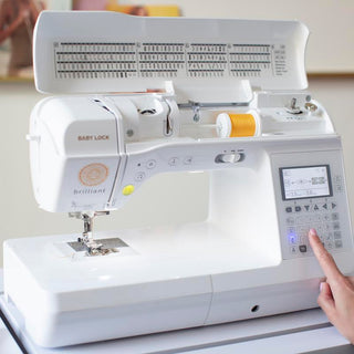 A person is pointing at a Baby Lock Brilliant Sewing Machine.