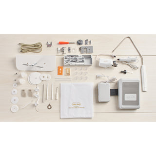 A white Baby Lock Ballad Sewing and Quilting Machine with various items laid out on it.