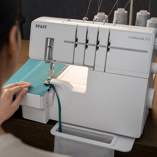 A woman is sewing on a Pfaff Hobbylock 2.5 sewing machine from the brand PFAFF.