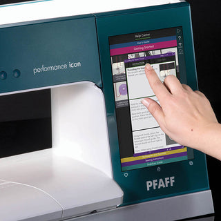 A hand uses the touchscreen display of the PFAFF Performance Icon, viewing threading instructions in its built-in help center within the brand's largest working area.