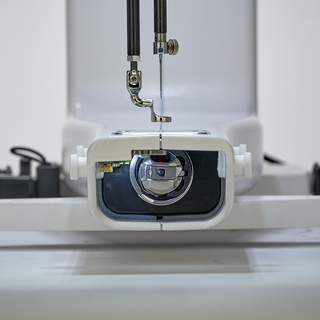 Close-up of a Baby Lock 20" Regalia Stationary Machine With Table And Insert's needle and presser foot, focused on threading and details, against a blurred background.