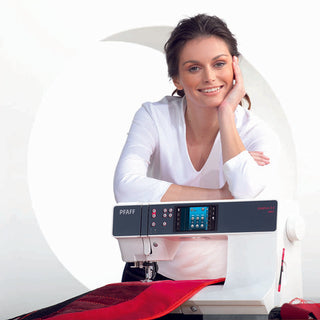 A woman in a white shirt smiles at the camera as she leans on a PFAFF Creative 3.0 sewing machine; red and black fabric under the needle highlights unique embroidery made with the Exclusive Stitch Creator by PFAFF.