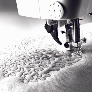 A close-up of the PFAFF Pfaff Creative 3.0 sewing machine stitching a freeform quilt pattern on light fabric, showcasing its intricate embroidery capabilities.