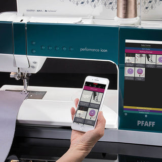 Someone holds a smartphone showing sewing instructions in front of the PFAFF Performance Icon sewing machine, which offers the largest working area and an advanced touchscreen interface.