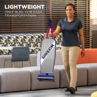 A woman holding an Oreck Commercial XL2100RHS Commercial Upright Vacuum Cleaner XL in a lobby.