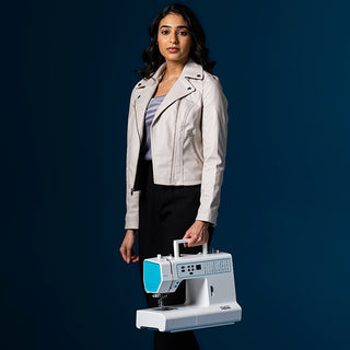 A woman holding a Smarter By Pfaff 260c sewing machine on a blue background.
