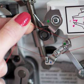 A person is using a Baby Lock Vibrant 4/3/2 Thread Serger sewing machine to sew a piece of fabric.