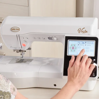 A woman is using a sewing machine with an ipad.