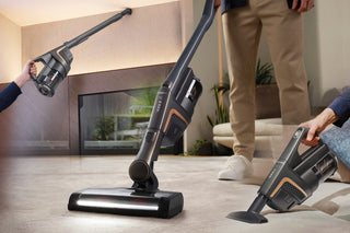 A man is using a vacuum cleaner on the floor.