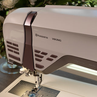 A Husqvarna Viking sewing machine is sitting on a table with flowers.