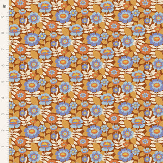 Tilda Wallflower Beverly Caramel TIL100612 by Fabric by Tilda features blue, orange, and beige floral prints with green leaves on a brown background and a vertical inch ruler for scale. Made of 100% cotton.