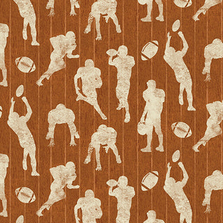 1683838B 16838-38 Kick Off Rust Skyline Studio TOUCHDOWN Fabric features white silhouettes of football players and footballs over a textured, vertical-striped brown background.