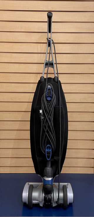 An Oreck Magnesium LW1500RS vacuum cleaner sitting on top of a blue wall.