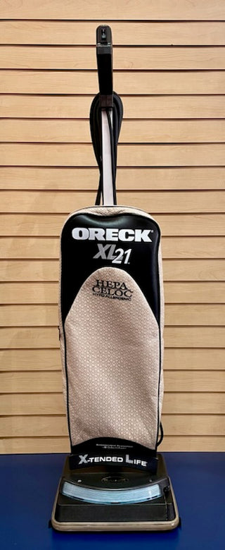 Reconditioned Sew & Vac Oreck XL - Certified Reconditioned vacuum cleaner with a beige and black color scheme, positioned against a wooden slat background.