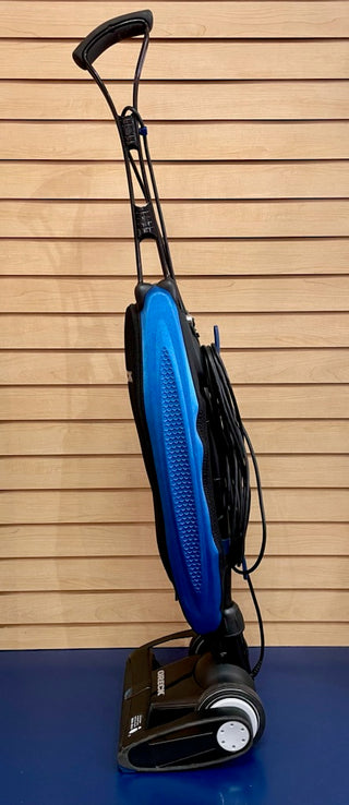 A Certified Reconditioned Oreck Magnesium LW100, a blue and black Sew & Vac vacuum cleaner, sitting on top of a blue wall.