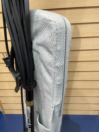 A light gray, knitted blanket draped over a wooden chair in great condition, with Oreck XL vacuums leaning against the chair.