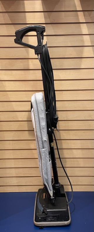 An Oreck XL upright vacuum cleaner with a new bag and belt, featuring a black handle and base, wrapped power cord, standing against a wooden slat wall.