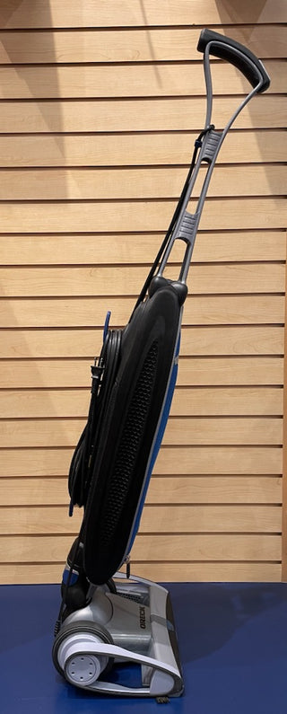 An Oreck Magnesium vacuum cleaner in great condition on a blue floor.