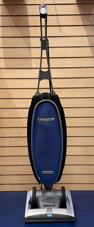 A blue and black Oreck Magnesium bag hanging on a hook, like-new parts.