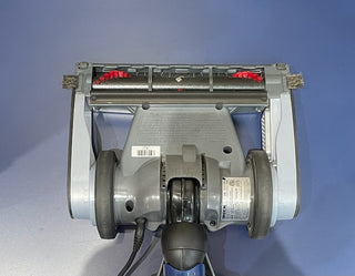Bottom view of a Sew & Vac Oreck Magnesium LW1500 Vacuum - Certified Refurbished showing brushes and wheels against a blue background.