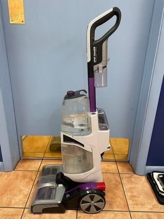 A certified refurbished Hoover Smartwash Pet Complete Carpet Cleaner in purple and gray placed in a room with tiled flooring and blue walls.