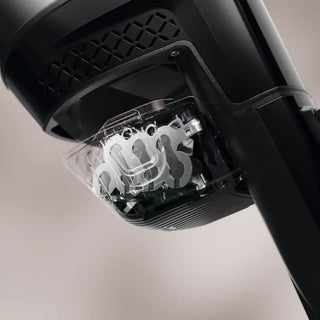 Close-up of a black electric shaver, highlighting the metal shaving blades and clear protective cover beneath the head—evoking the sleek design characteristic of 2-Miele’s Triflex HX3 Cordless Stick Vacuum in Brilliant White.