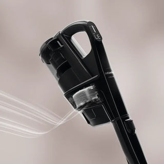 Close-up view of the Miele Triflex HX3 Cordless Stick Vacuum in Brilliant White, by 2-Miele, highlighting the visible dust container and HEPA filter in use, with air flow depicted by white lines.
