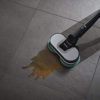 A Miele Triflex HX3 Aqua Plus Cordless Wet & Dry Vacuum by 2-Miele in Obsidian Black is effortlessly tackling a brown liquid spill on a tiled floor.