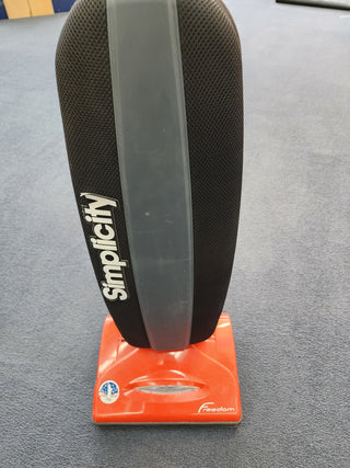 A black and orange Used Simplicity S10CV Cordless Vacuum sitting on top of a table.