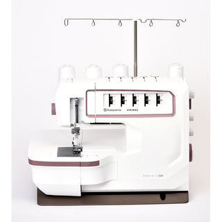 A white Husqvarna Viking Amber Air S500 serger from Imagine Sewing & Vacuum, featuring air threading, four thread spools, and multiple dials, is displayed against a plain white background.