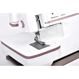 Close-up of a white and pink Husqvarna Viking Amber Air S500 sewing machine from Imagine Sewing & Vacuum, showing the needle area and body with advanced air threading technology for easy setup.